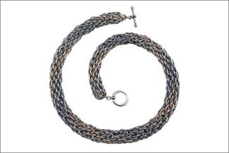 A metal woven necklace laid in a spiral