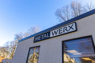 Outside view of a tan building with a large sign that says Metalwerx