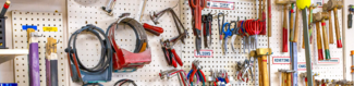 A peg board wall of jewelry tools like sawblades, hammers, pliers, and more