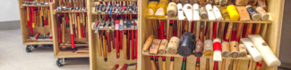 Four wooden carts holding various jewelry hammers and mallets for metal work